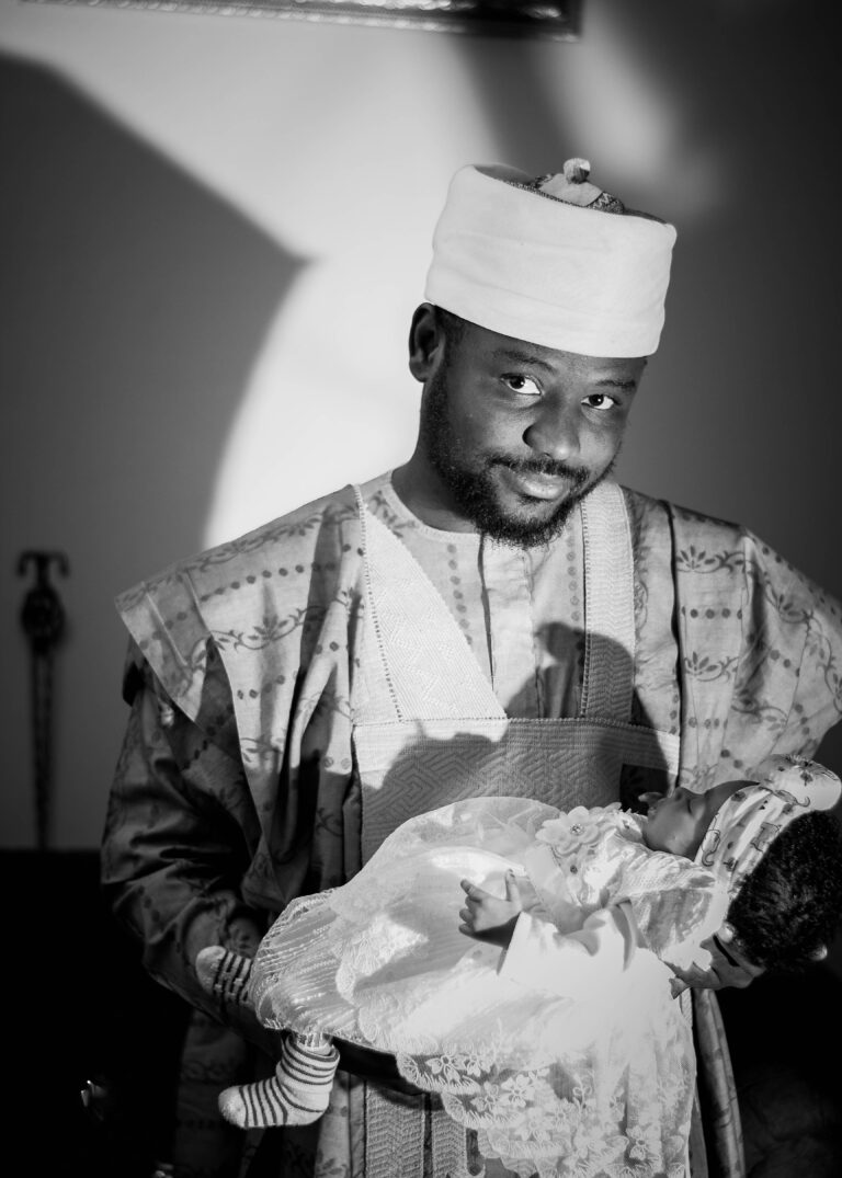 Father at a traditional African naming ceremony holding his baby, photo by the northern lense on Pexels