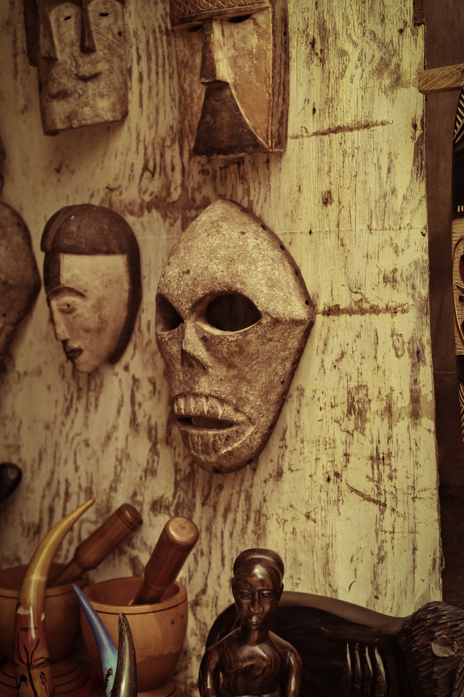 A collection of traditional African masks and carved artefacts in warm light