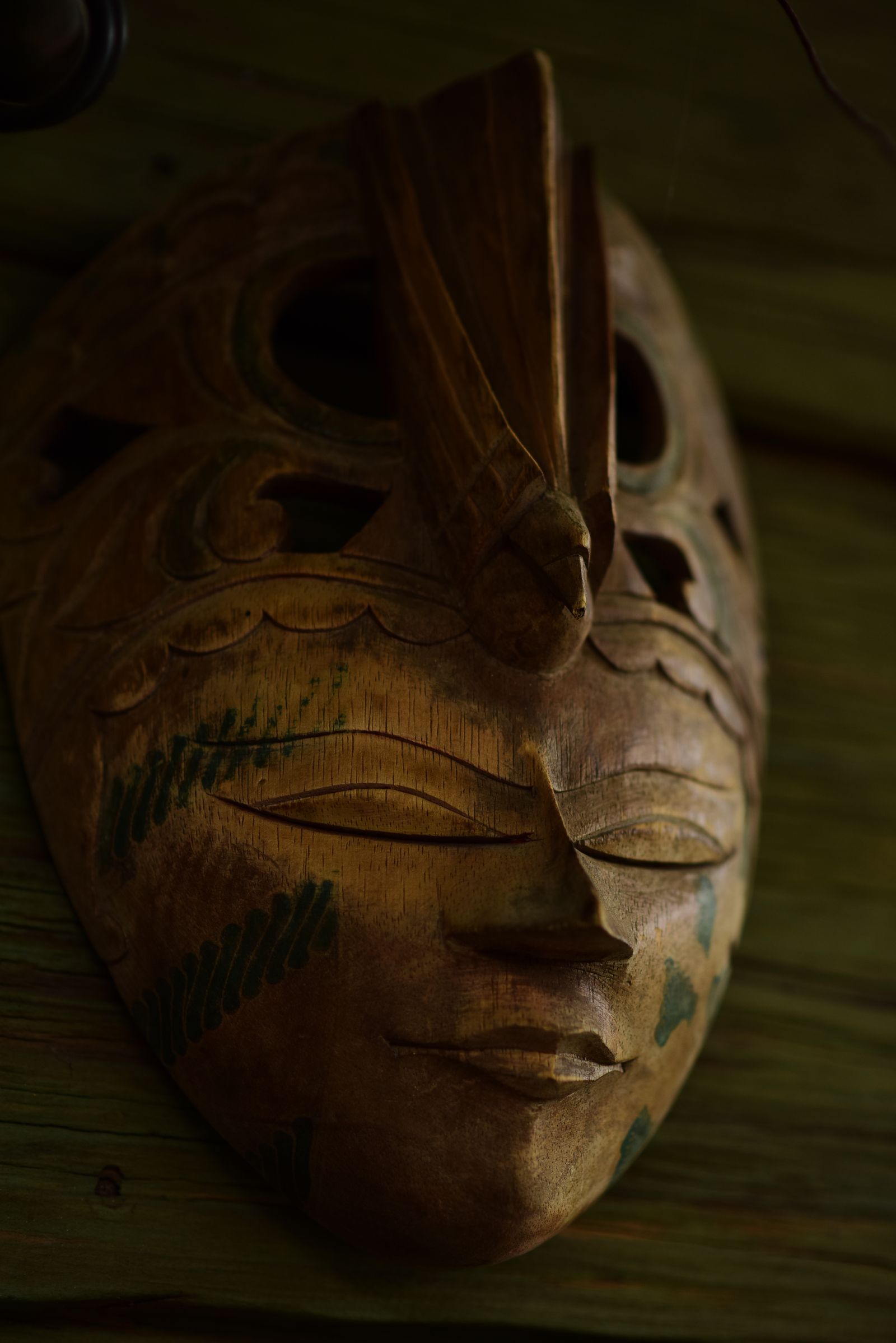 A carved wooden African mask showing grain, tooling and applied pigment