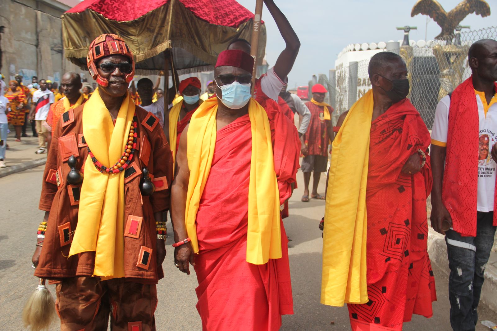 Chiefs in yellow and red traditional dress walking in procession at a cultural ceremony in Accra, Ghana