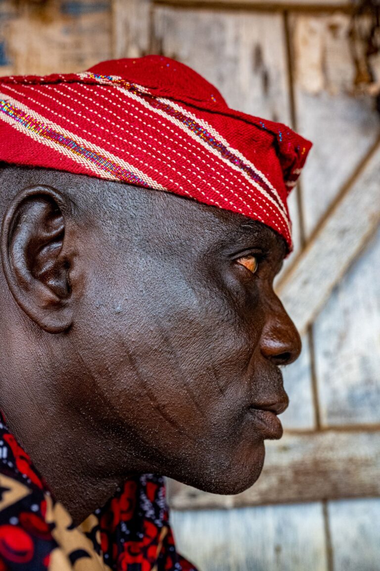 Profile portrait of an older Nigerian man in a red cap and traditional attire, Lagos