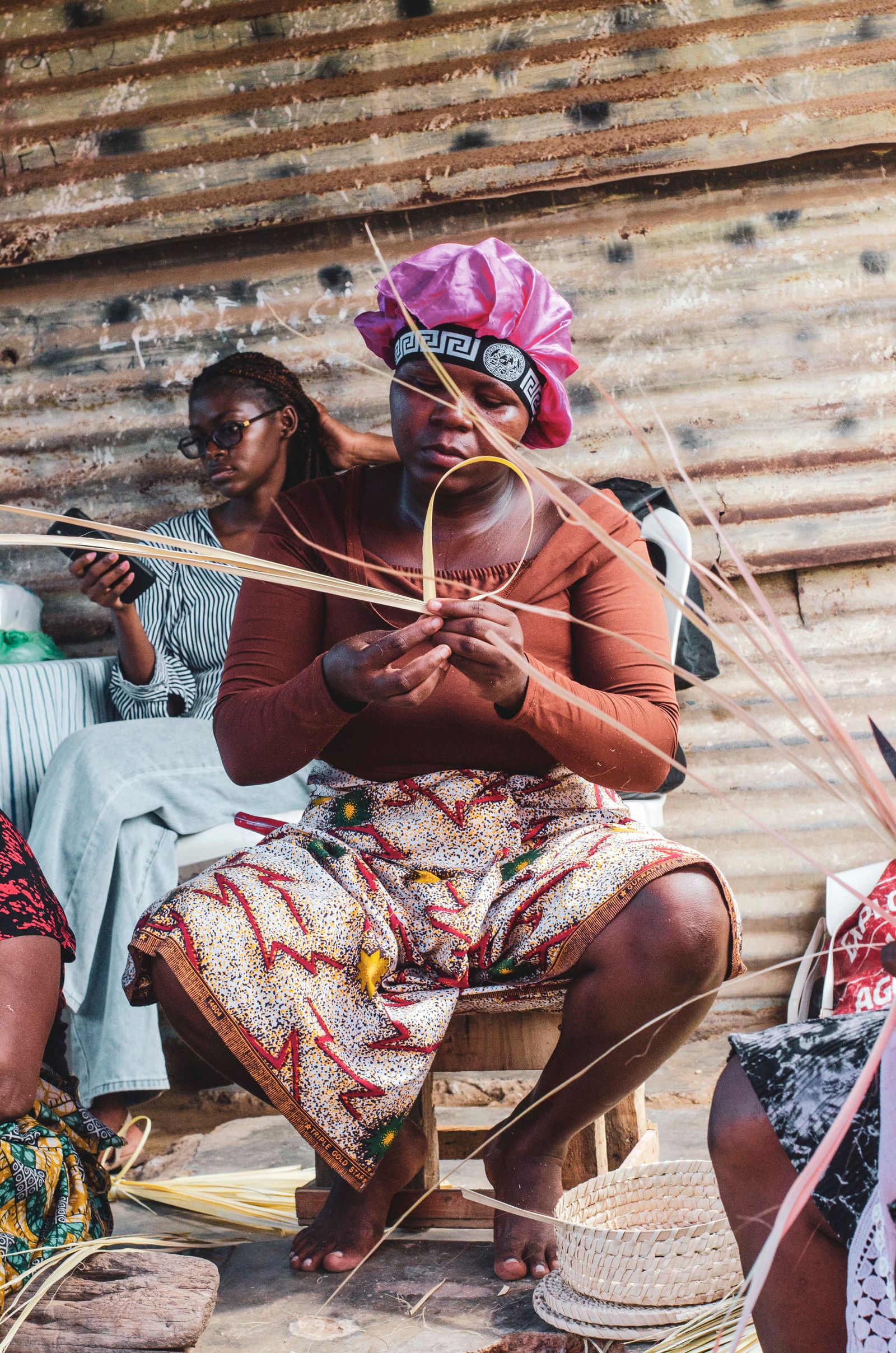 Two women weaving by hand in a traditional workshop